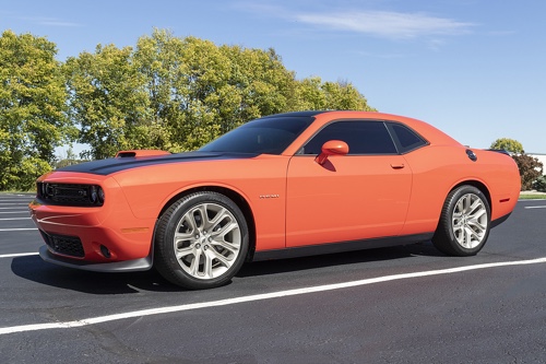 Nitrous: There's Nothing Funny About This Speed with Accelerate Auto Repair in Rowlett TX; image of side view of orange dodge challenger with black racing stripes parked in parking lot at shop