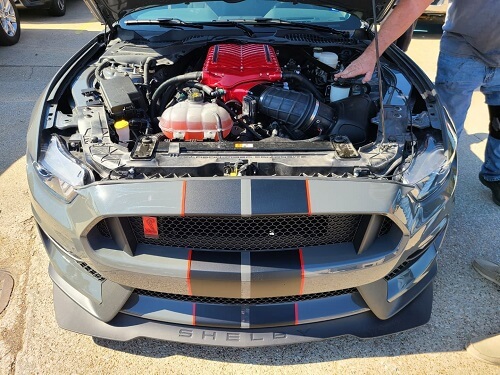 Non-negotiable Preventative Maintenance | Accelerate Auto in Rowlett, TX. Closeup image of a car mechanic doing engine check and preventative maintenance on the engine of Shelby GT350R.