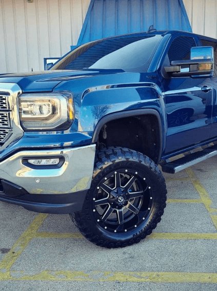 Image of a blue GMC pickup with performance mods that came in for auto repair services, parked in front of Accelerate Auto Repair in Rowlett Tx