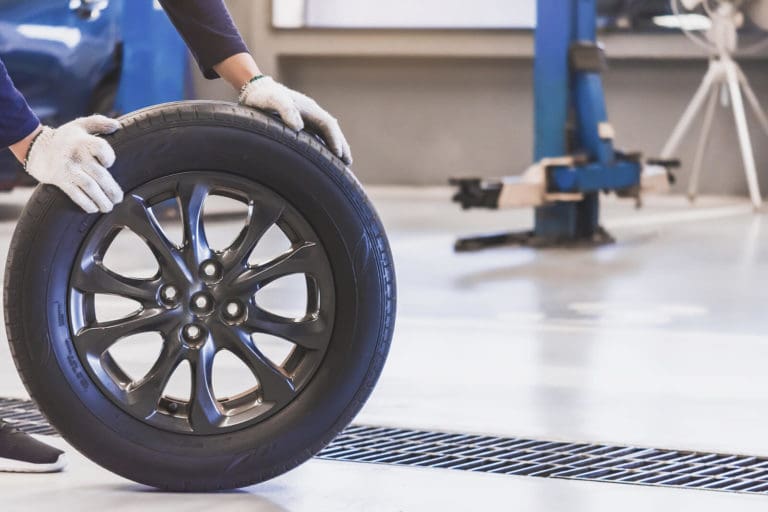 Technician handling a wheel and tire in a repair shop