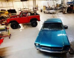 Careers at Accelerate Auto Repair in Rowlett, TX. image of aerial view of inside the shop with turquoise 70's mustang, red off road jeep and other cars being maintained