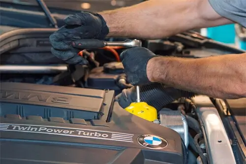 How to Make Your BMW Last Over 100,000 Miles or More! | Accelerate Auto Repair in Rowlett, TX. Closeup image of an auto mechanic performing repair and maintenance on a BMW under the hood.