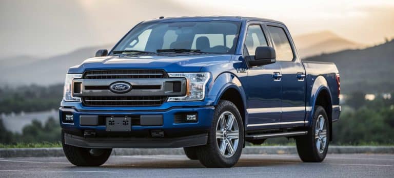 Blue Ford F-150 pickup truck parked at sunset