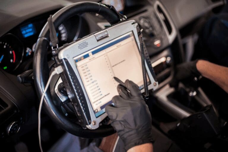Technician running a vehicle diagnostic on a laptop scan tool