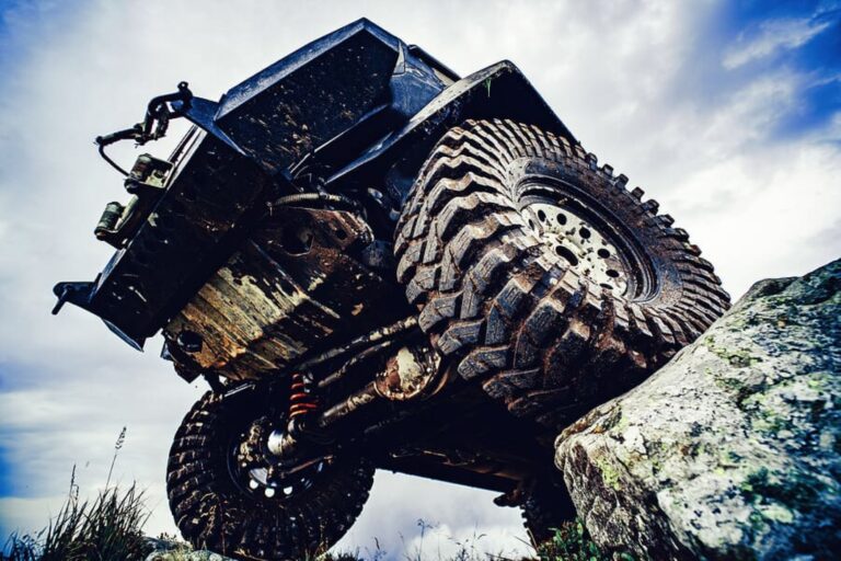 Underside view of a lifted off-road Jeep showing the solid front axle and steering components
