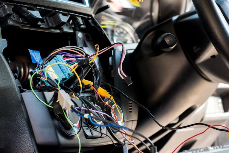 Wiring harness and connectors exposed behind a vehicle dashboard during electrical repair.