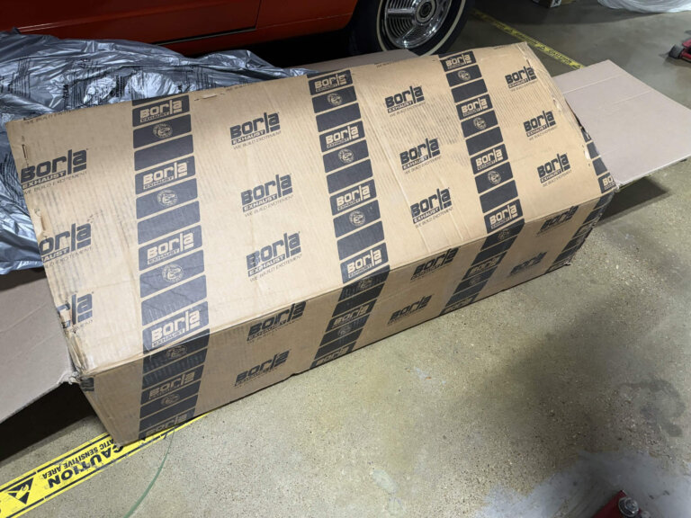 A large Borla exhaust shipping box inside the Accelerate Auto Repair shop.