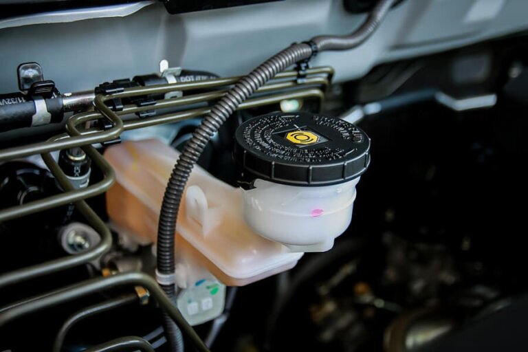 Close-up of a vehicle’s brake-fluid reservoir and cap under the hood.