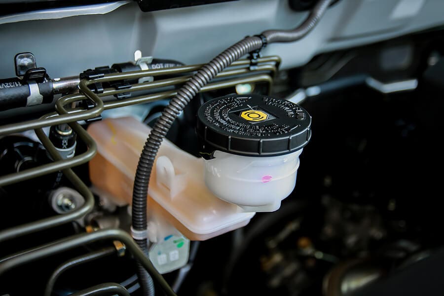 Close-up of a vehicle’s brake-fluid reservoir and cap under the hood.