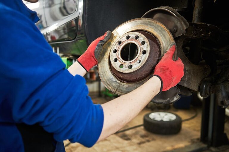 An auto technician replacing the brake pads on a vehicle.