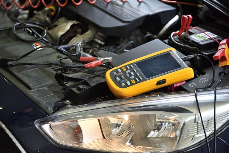 Diagnostic equipment connected under the hood of a car.