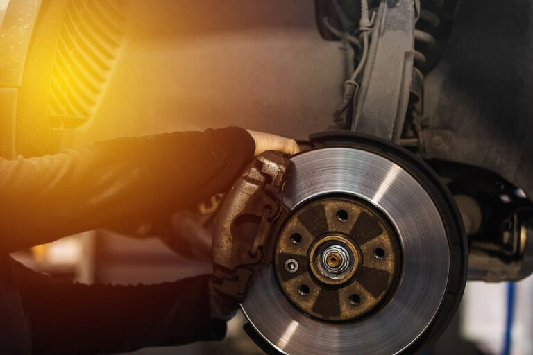 A technician fitting a brake caliper over a brake rotor on a wheel hub.