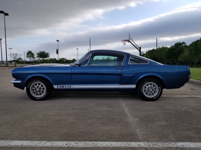 A blue classic Ford Mustang fastback parked outside.