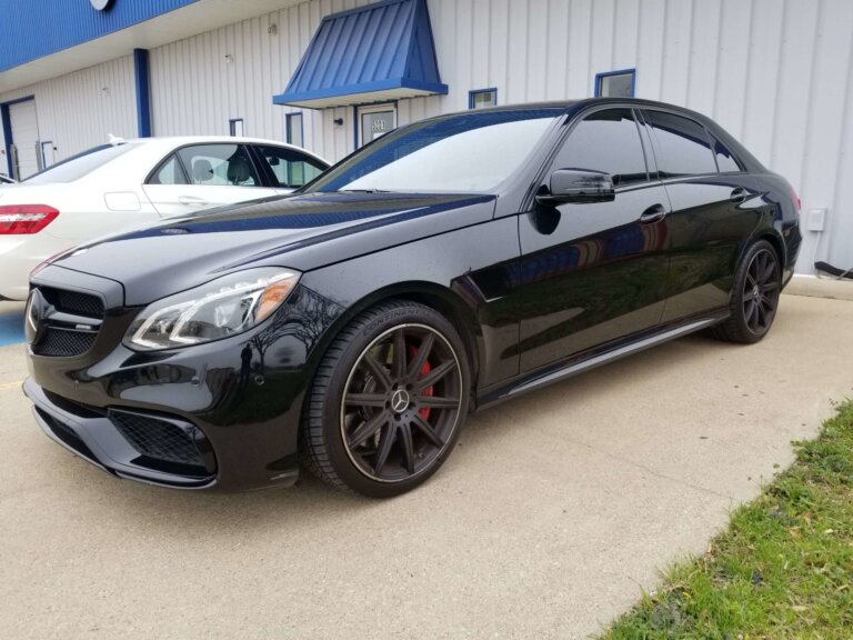 A black Mercedes-Benz sedan parked outside a shop building.
