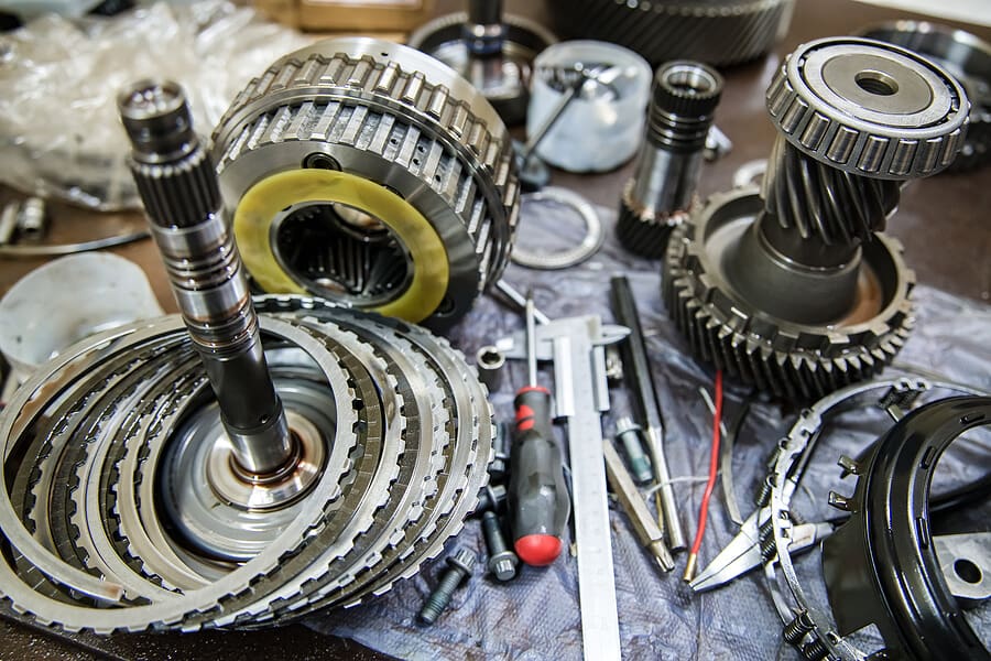 Automatic transmission clutch packs, shafts and gear assemblies arranged on a workbench.