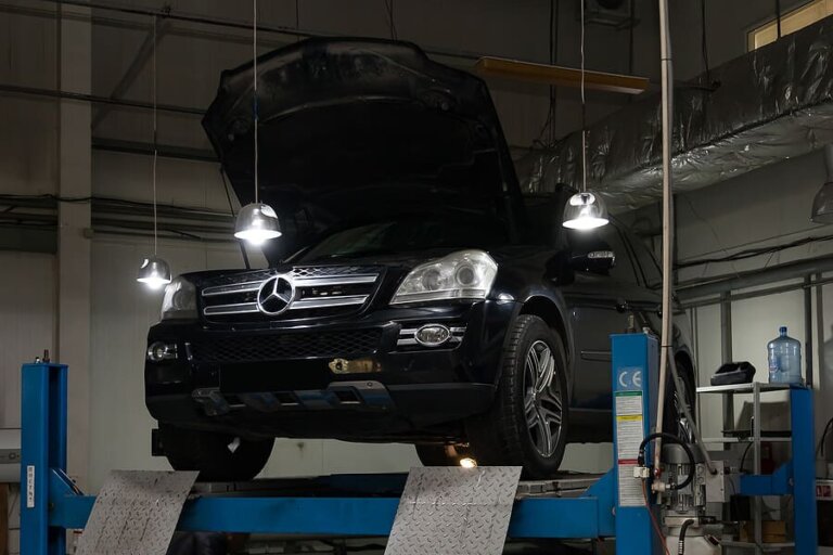 A Mercedes SUV raised on a lift in a repair garage.
