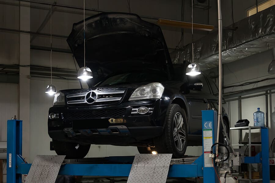 A Mercedes SUV raised on a lift in a repair garage.