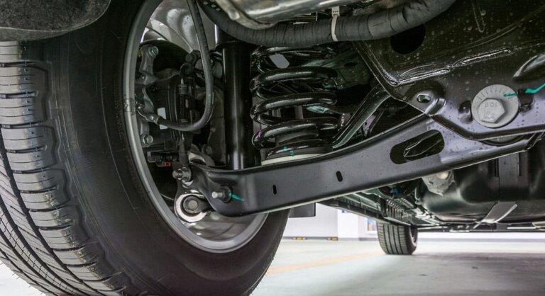Front wheel, tire, coil spring, shock and suspension arms viewed from beneath a vehicle.