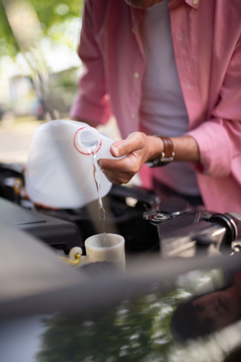 Person pouring coolant into a car engine reservoir