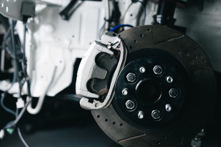 Brake caliper and drilled brake rotor on a car in a workshop