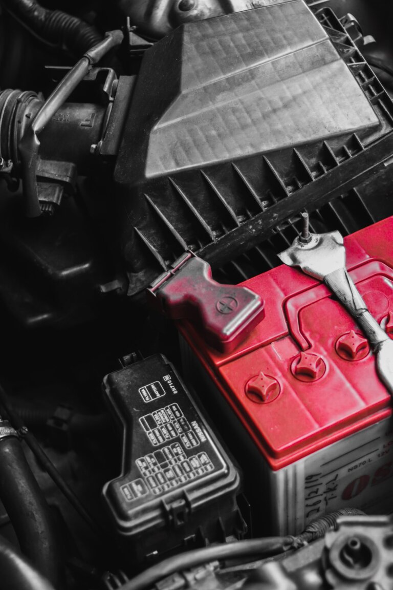 Car battery in an engine bay with a wrench beside it