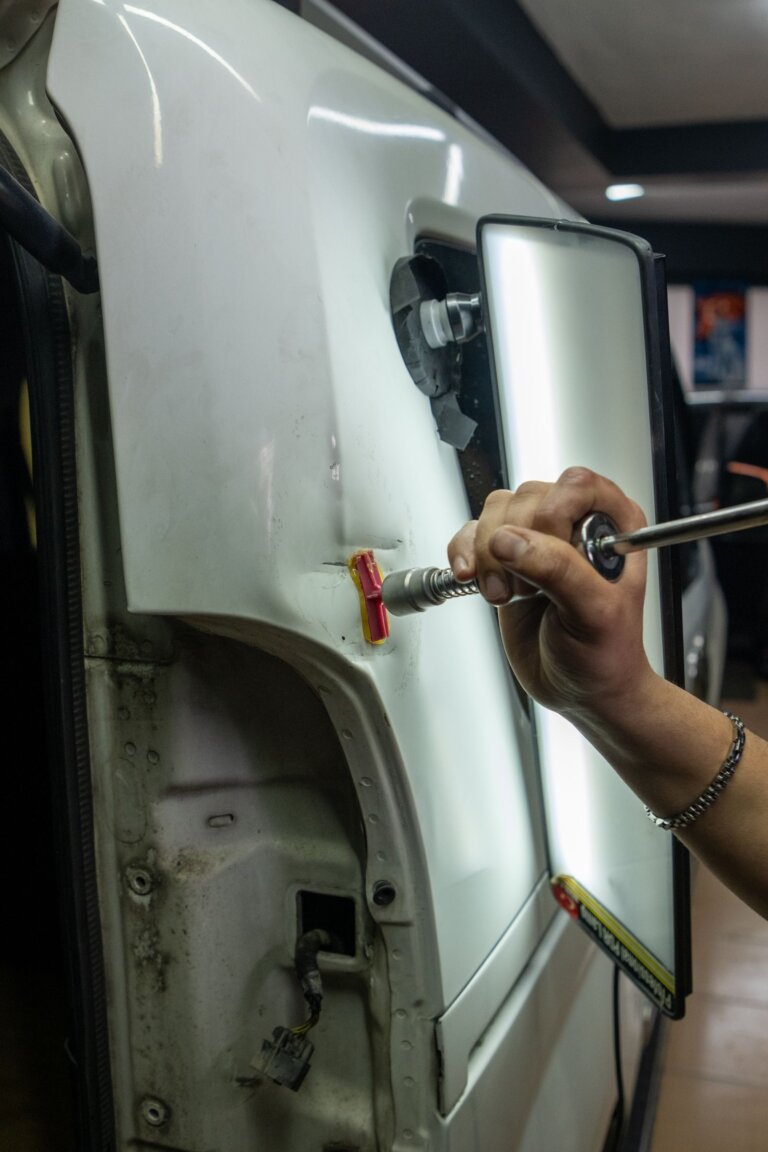 Close-up of a technician repairing a dent in a car body panel