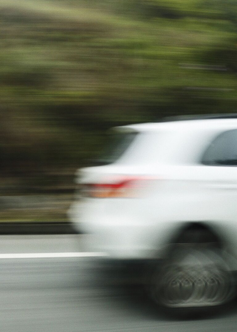 White car driving on a highway, shown with motion blur