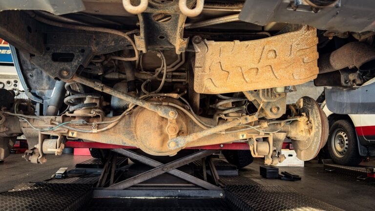 Underside view of a car suspension and control arms during repair