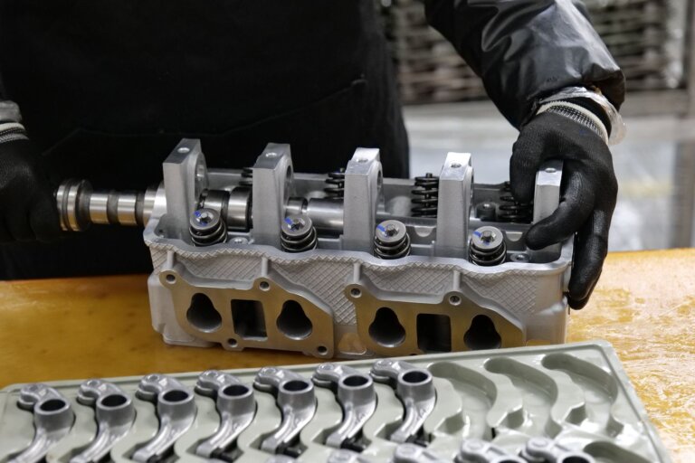 Mechanic assembling an engine cylinder head on a workbench