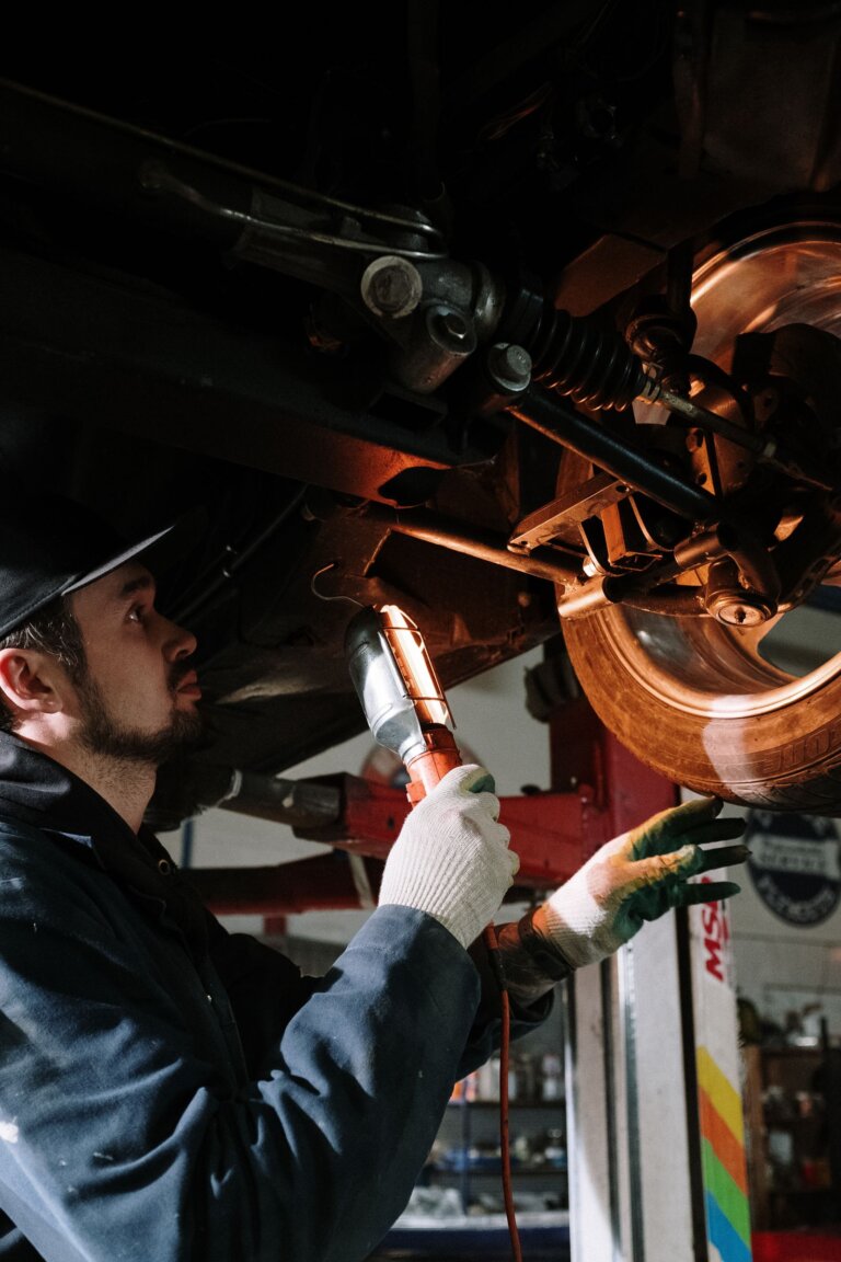 Mechanic inspecting a car suspension with a flashlight