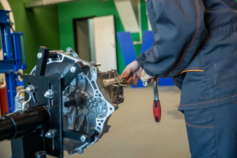 Mechanic working on a removed car transmission in a workshop