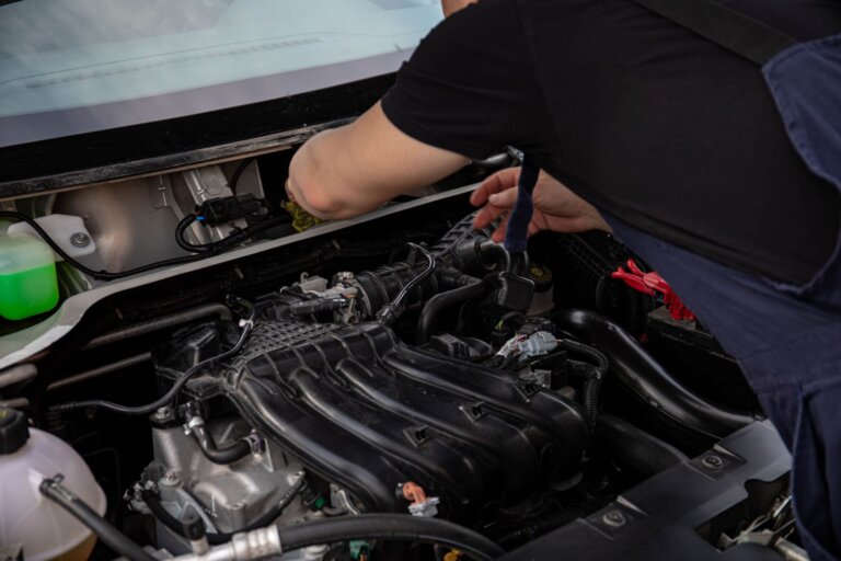 Mechanic working on a car engine with the hood open