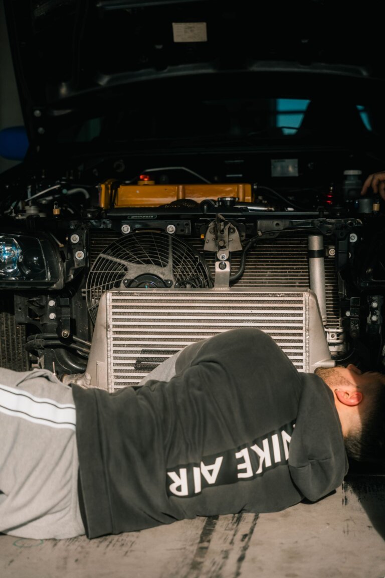 Mechanic working on a car radiator at the front of the engine bay