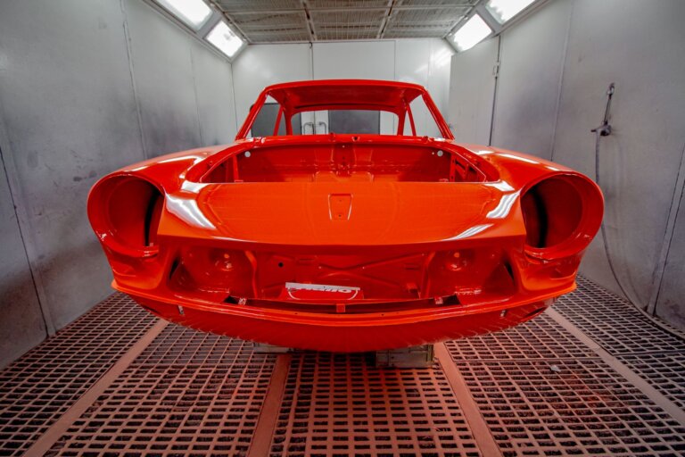 Freshly painted red car body inside a paint spray booth
