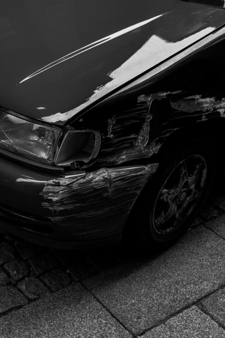 Damaged and scratched front fender on a dark car
