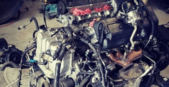 A removed vehicle engine assembly with exposed components and wiring.